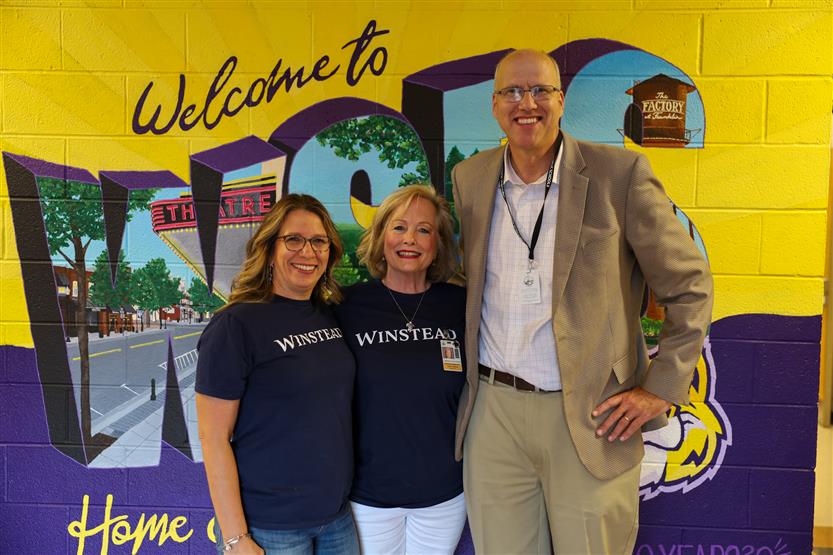 Superintendent Jason Golden and teachers stand in front of a mural